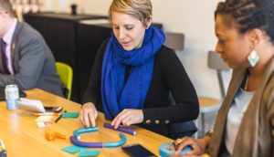 Educators sit at a table prototyping using post-it notes and found materials