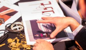 Close up of a designers hands over an open portfolio book with brightly colored illustration.