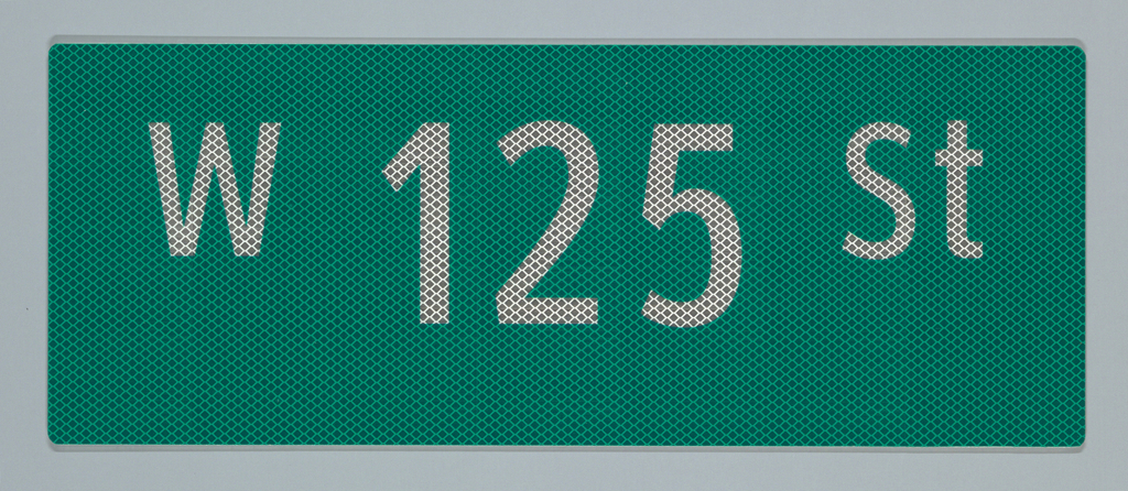 Image features a green, New York City street sign composed of a landscape-orientation rectangle with "W 125 St" in white letters. The "125" is largest, in the middle, and the other text is slightly smaller, on either side, and higher up. The material of the sign will reflect light, and appears in this image with a small diamond pattern, like a chain-link fence. Please scroll down to read the blog post about this object.
