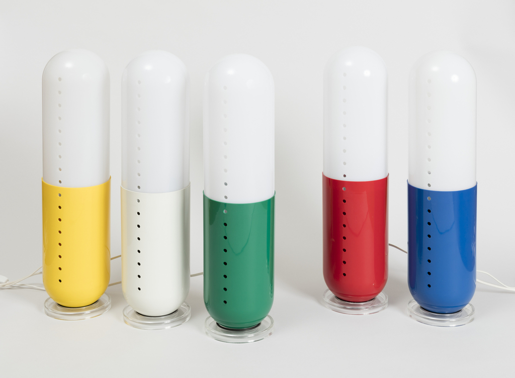Image features a group five floor lamps in the shape of giant pills, each with a white top and a base in a different color: yellow, white, green, red, and blue. Please scroll down to read the blog post about this object.