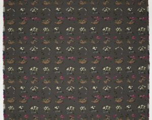 Image features a woven textile with a charcoal gray ground and a pattern of fragmented color wheels, made up of small squares of greens, gray-blues, browns, pinks, and off-whites. Please scroll down to read the blog post about this object.