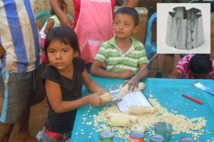 Two children under the age of five, who evidently live in humble rural circumstances, are removing the kernels from ears of corn using a small metal device that looks similar to a cookie cutter.