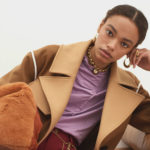Alexis Sundman, a pretty model with a light brown complexion with her hair tied back, tilts her head and toys with an earring. She looks casual but cool in her brown wool coat and purple blouse.