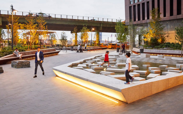 In an urban plaza, children play on artificial 