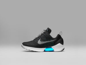 A black sneaker with a white sole. There is a light-up blue insert in the sole. The shoe features a gray Nike "Swoosh" logo