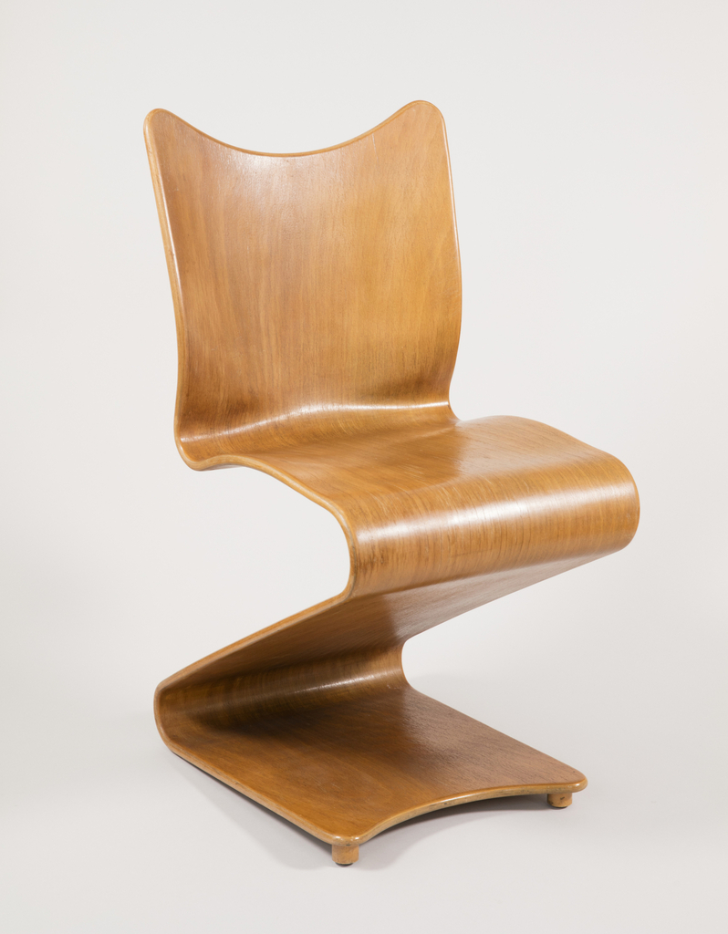Image features a cantilevered chair of ribbon-like form, made of natural brown laminated plywood; the front feet slightly raised. Please scroll down to read the blog post about this object.
