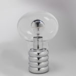 Light bulb-shaped clear glass globe enclosing clear glass light bulb with silvered top; cylindrical, chromed metal base in shape of socket with horizontal ridges.