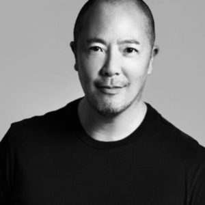 Black and white headshot of Derek Lam wearing a black T-Shirt