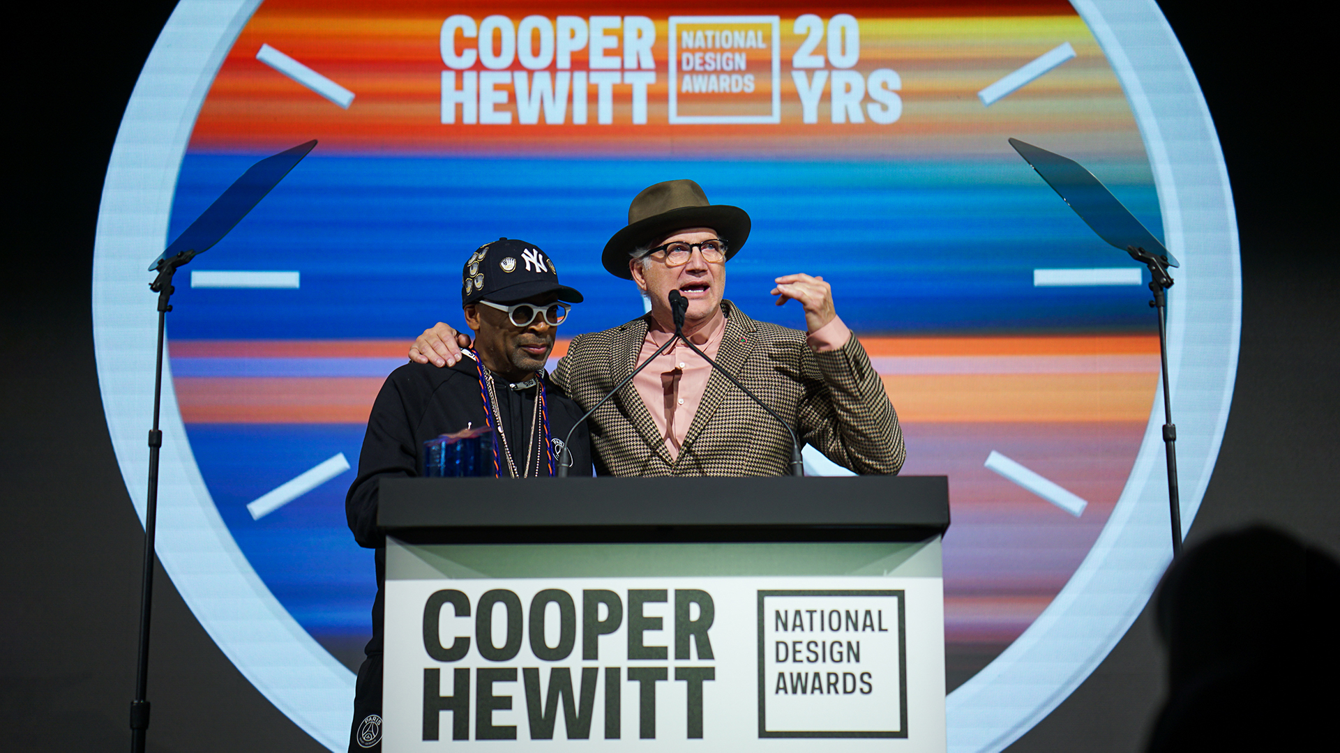 Tinker Hatfield, NDA winner, has his arm around Spike Lee, while standing at a podium at the National Design Awards