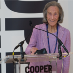 Barbara at a podium in Cooper Hewitt, wearing lavender