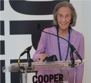 Barbara at a podium in Cooper Hewitt, wearing lavender