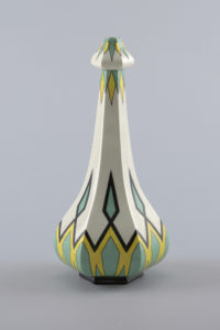 Image features a six-sided bottle-form vase with a bulbous bottom, ascending into a narrow neck, and a rounded arrow like top. The white body is decorated with a symmetrical pattern of diamonds in black, yellow, and mint green. Please scroll down to read the blog post about this object.