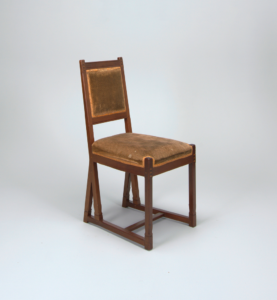 Image features a brown wooden chair with straight legs and low stretchers, slightly angled back and rectangular seat, both upholstered in tan to brown fabric. The legs and frame back are decorated with square ebony inlay. Please scroll down to read the blog post about this object.