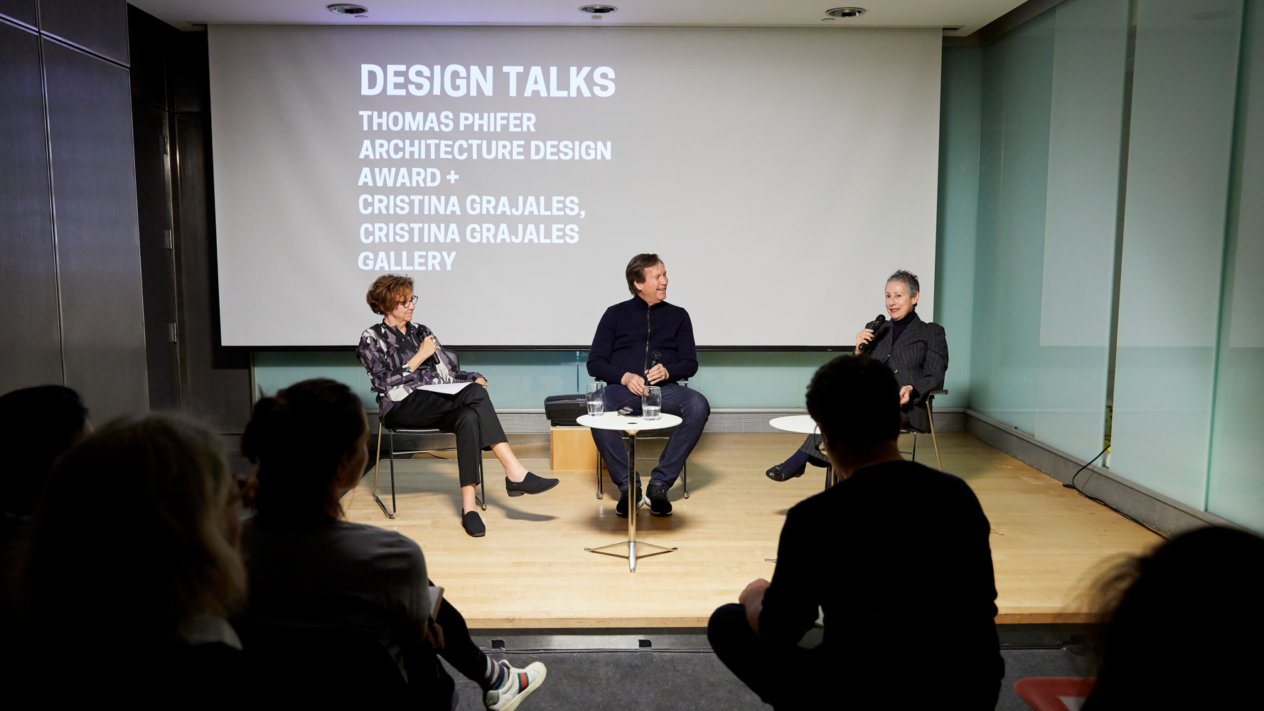 Image of three people on stage in front of an audience. On the left is Matilda McQuaid, middle is Thomas Phifer, on the right is Cristina Grajales