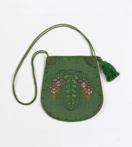 Image features: a U-shaped drawstring purse in green, with a stylized design of fuchsias in two greens, violet, two pinks, yellow and white. Long green cord with tassel. Please scroll down to read the blog post about this object.