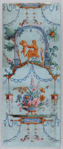 Image features wallpaper showing a seated female figure holding a cupid-like figure, amidst swags and multicolored floral decoration on a blue ground. Please scroll down to read the blog post about this object.
