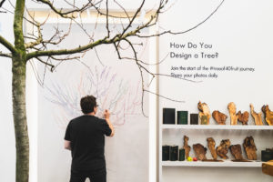 Designer Sam Van Aken draws a colorful diagram of his Tree of 40 Fruit on a wall behind the actual Tree of 40 Fruit