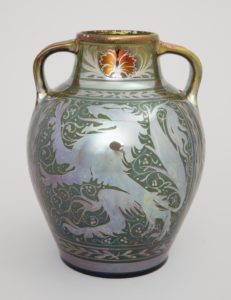 Image features a two handled ovoid vase with a lusterware glaze, ornamented in resist copper-colored decoration. Surface decoration consists of two heraldic lions along with foliage and twining vines. Please scroll down to read the blog post about this object.