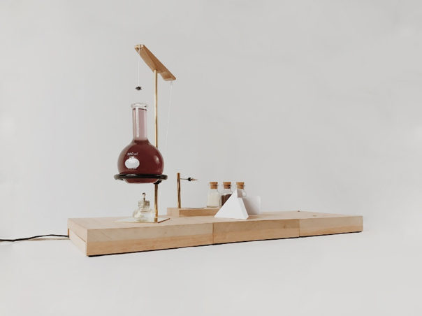 A simple machine fashioned by hand featuring a large beaker full of a red liquid