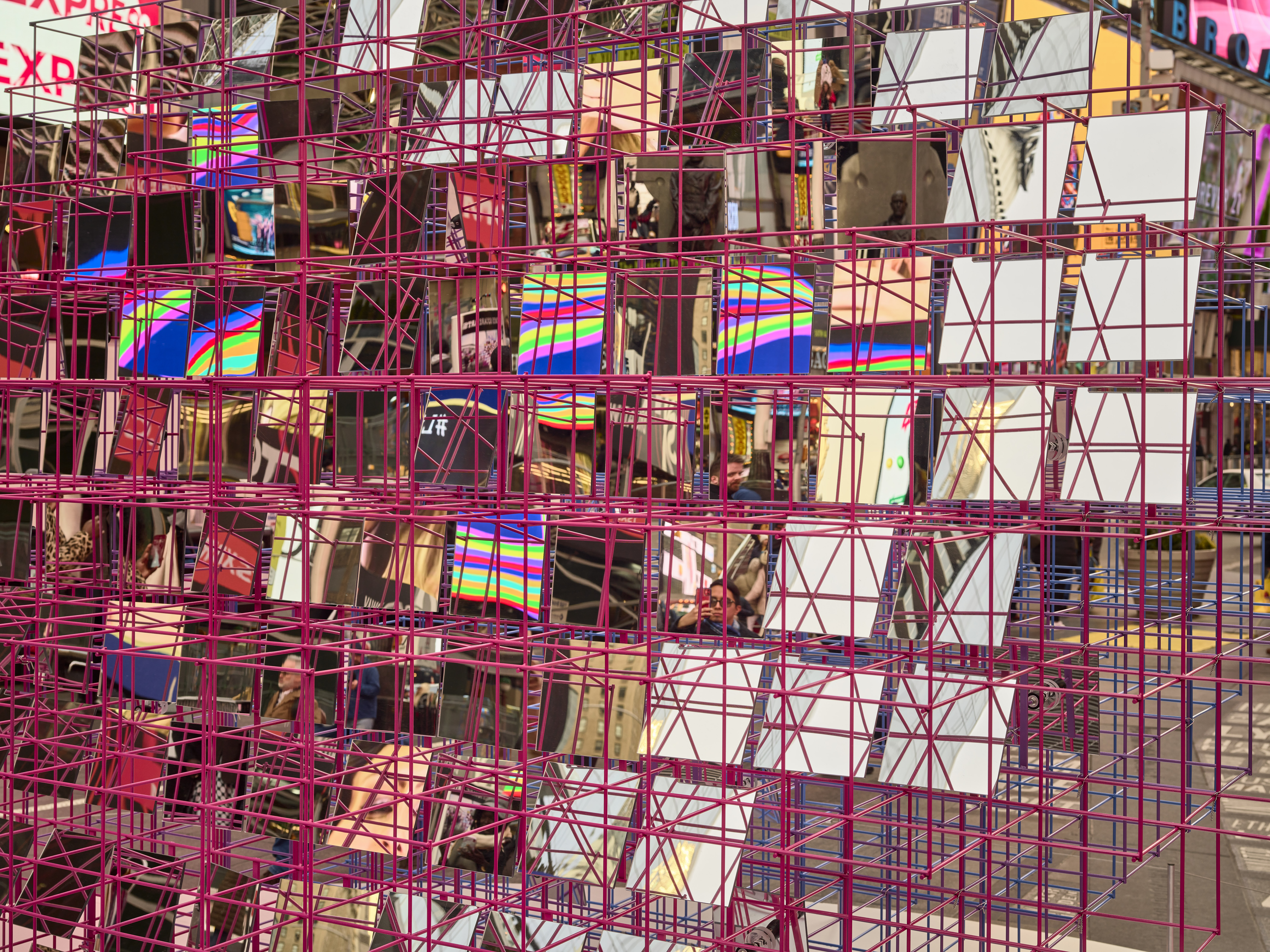 Detail image of public art installation. Red metal rod large grid with square mirrors inside grid reflecting the surroundings.