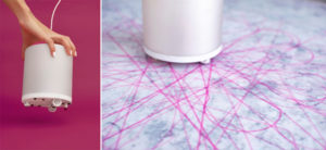 Diptych. Left: A woman's hand holds a machine that is a white cylinder with a magenta marker and small wheels on the bottom. Right: Lines drawn by the cochineal machine form an asterisk-shaped design