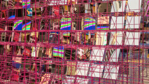 Detail image of public art installation. Red metal rod large grid with square mirrors inside grid reflecting the surroundings.
