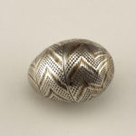 Silver egg-shaped container with gold chevron pattern