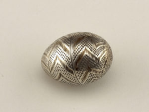Silver egg-shaped container with gold chevron pattern