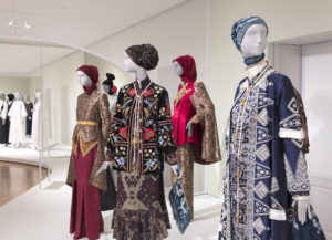 A view of the Cooper Hewitt galleries with four ensembles on mannequins.
