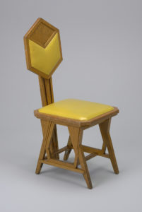 A oak side chair with yellow leatherette cushions on the square seat and back