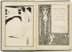 Image features the frontispiece and title page of the book, Salome: A Tragedy in One Act, printed in black ink on white paper. The frontispiece, shows a moon-shaped head in the night sky, obscured by clouds; two figures to the right, one nude and one clothed, stare at the head-as-moon. The title page, opposite, shows a large vertical block containing the text "Salome: A Tragedy in One Act" and information about the writer, illustrator, and publishers. Surrounding the block is ornate foliage in which two fantastical nude figures—one with horns and one with wings—peer back at the reader. Please scroll down to read the blog post about this object.