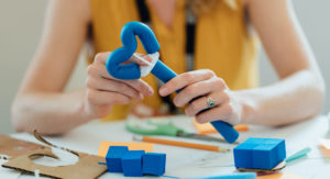 This image shoes someone holding a prototype with both hands. Materials are around the table.