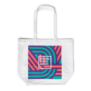 A white tote with a square graphic. The graphic features green, purole, and pink intersecting lines with National Design Awards Cooper Hewitt in white at the center.