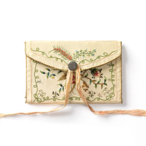 Cream-colored fabric envelope with pink ribbon and floral embroidery