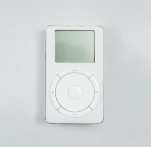 Flat rectangular handheld device with wheel in center and buttons forming the edge of the wheel.