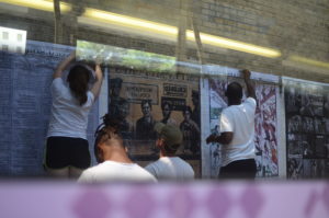 Image of Colloquate Design's Paper Monuments project. 2 people hang posters