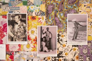 Three black and white photographs are hung on a wall covered in colorful textile patterns featuring botanical and zoological themes.