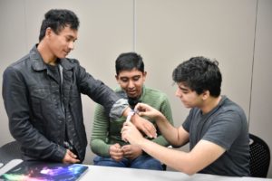 A young Project Invent student tries a prototype on a user's wrist