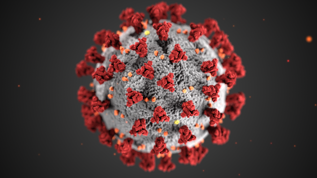 A microscopic rendering of a round virus with triangular red protrusions and orange dots