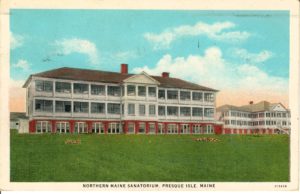 Color postcard of a three-story sanatorium with thirteen semi-enclosed sleeping porches on the upper two levels, rooms with full-length windows on the ground level, and a lawn in the foreground