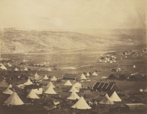 Sepia photograph showing several white cone-shaped tents pitched throughout a field