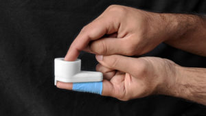 Side view of a pair of light-skinned hands holding a white device, with a thick, flat bottom extending into a squat tube, between the index fingers of both hands