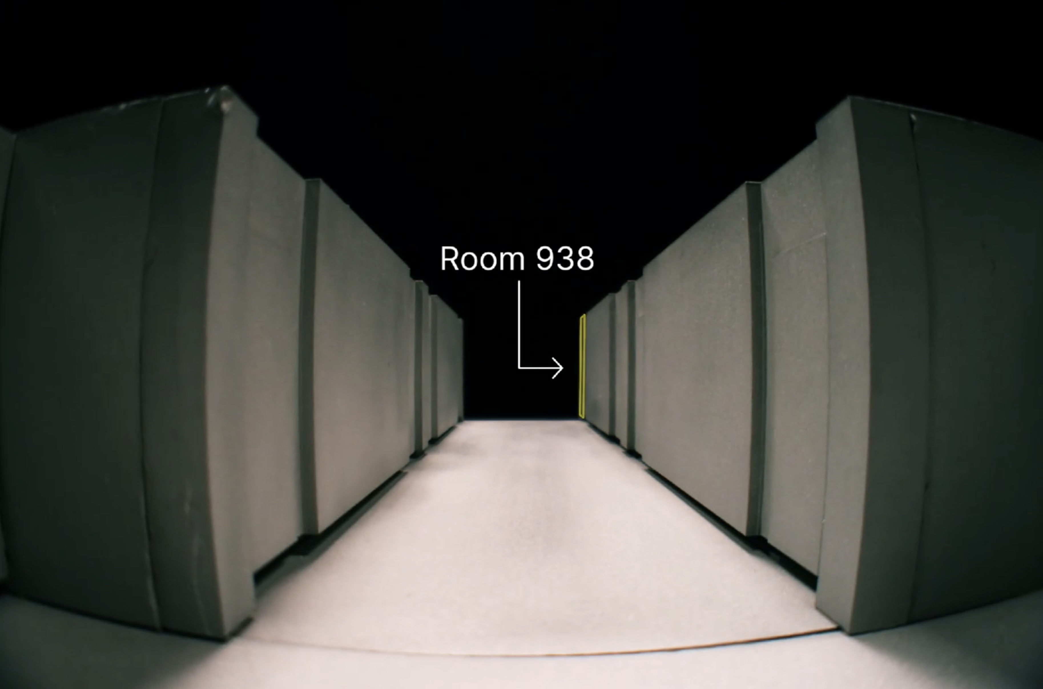 In a dark rendered hallway, walls recede on both sides. An arrow pointing to an open door at the end of the hall is captioned Room 938.