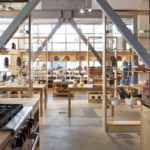 A photograph of a ceramics showroom. In the foreground is a stovetop and counter. In the background are various tables and display shelves with ceramics.