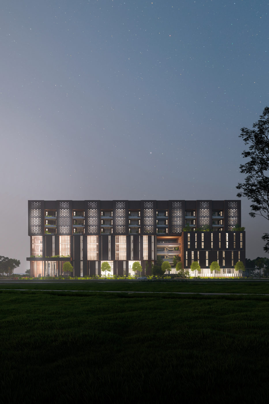 Distant exterior nighttime view of a long rectangular building that is brightly illuminated by windows of varying sizes across the full length of the building.