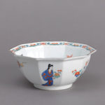 An octagonal white porcelain bowl decorated with flowers and a human figure.