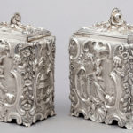 Rectangular silver box with scrolling organic designs surrounding scenic panels