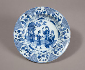 Blue and white intricately decorated circular porcelain basin, with a group of elegantly dressed figures in a landscape in the central bowl, the edge border decorated with alternating, repeating figural and geometric, Greek key motifs.