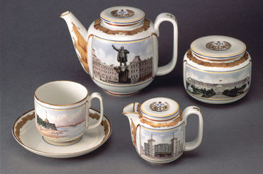 A four-piece porcelain tea set decorated with highly-detailed depictions of different landmarks in Leningrad and accented with ornate gold designs.