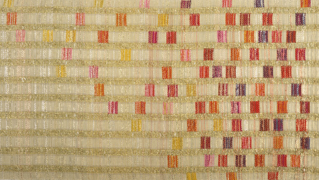 Vertical columns of light golden thread run down the length of a long textile, with vibrant squares of pink, purple, red, and yellow cascading down the columns.